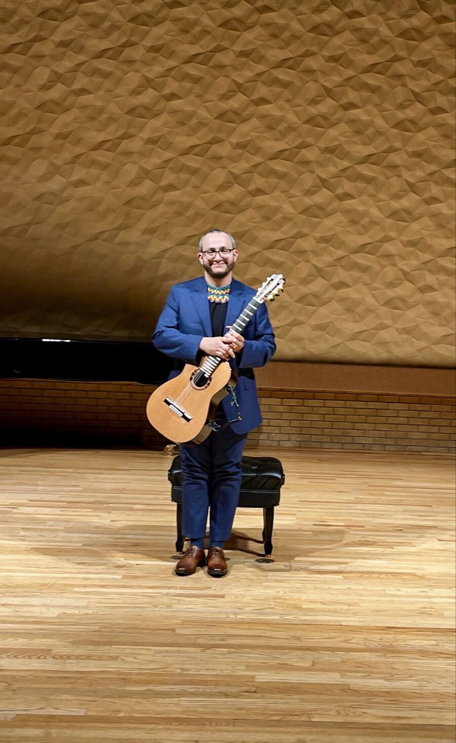 Andrés Arcila standing with classical guitar after a recital